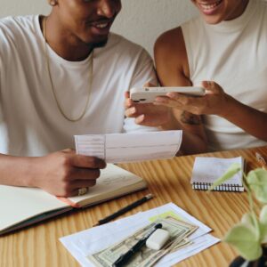 Smiling couple reviewing documents with a phone and money.